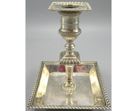 Edwardian silver candlestick with square dish base stood on four ball feet, baluster stem and gadrooned borders by Hawksworth