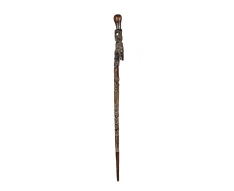 A Maori walking stickNew Zealandcarved a seated tiki and two kneeling tiki figures, with inset haliotis eyes, and bands of li