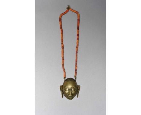 A Naga head chest ornamentNagalandbrass with scarifications and tusk-like ear ornaments, with orange and red glass beads,8.5c
