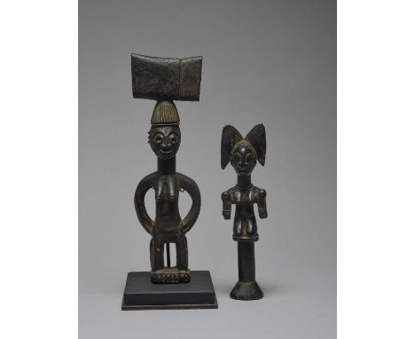A Yoruba Shango staff Nigeriacarved as a kneeling woman holding a club in each hand and with a thunder-axe headdress, wearing