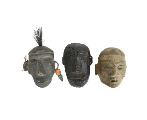 Three Naga carved wood head ornamentsKonyak, Nagalandone with punched dot tattoo decoration and pierced ears, 10cm high, anot