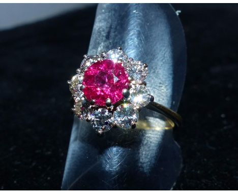 A yellow metal dress ring with a ruby and 8 diamonds in cluster setting, marks worn, test as 18 carat