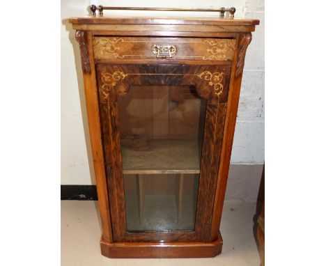 A late Victorian figured walnut music cabinet with shelf and compartments enclosed by glazed door, with inlaid trophy and str