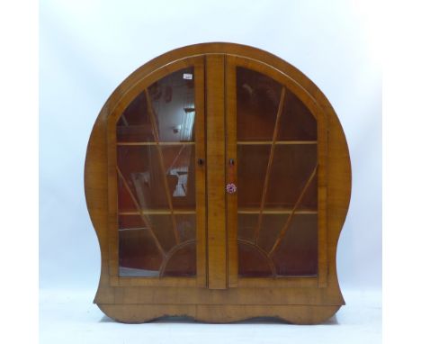 An Art Deco walnut display cabinet of Sun Burst design with two doors enclosing shelves raised on shaped base, H:123cm W:122c