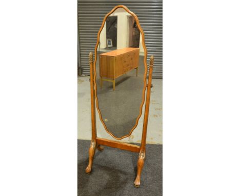Unknown - A walnut cheval mirror of scalloped oval form, the supports highlighted by silvered scroll capitals above four scro