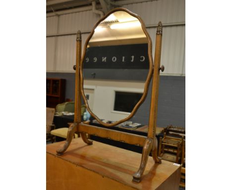 Unknown - A walnut dressing table mirror of scalloped oval form, the supports highlighted by silvered scroll capitals above f