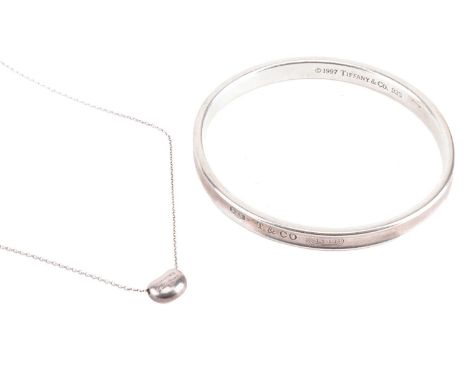 Tiffany &amp; Co. - an 1873 closed bangle and an Elsa Peretti bean charm on chain; the bangle struck with London assay marks 