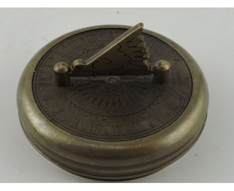 A travelling brass sun dial, of circular form incorporating a compass and folding gnomon, D. 7cm.