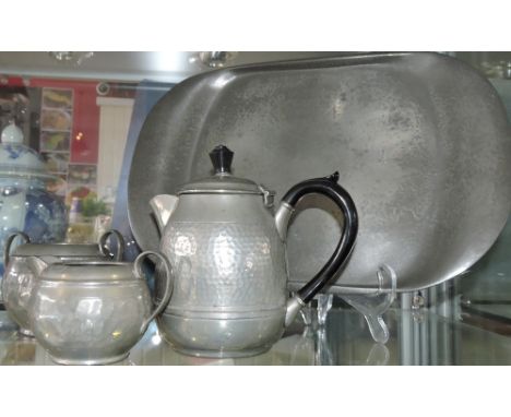 A pewter four piece tea service, including a tray, with a planished finish. 