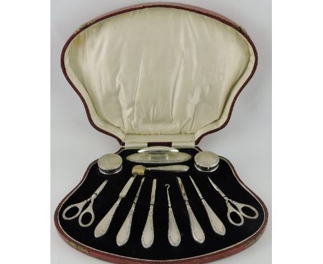 A comprehensive early 20th century silver-mounted manicure set, Birmingham 1902, engine turned with a foliate border, within 