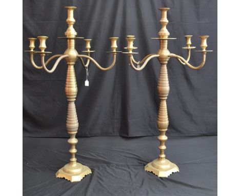 A pair of massive brass floor standing five light candelabra with campana shaped sconces, ring turned columns, mid century