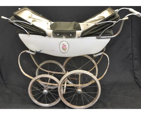 A vintage Silver Cross Twins pram, white strap work body and cradle, oval floral central panels, four multi spoked wheels, tw