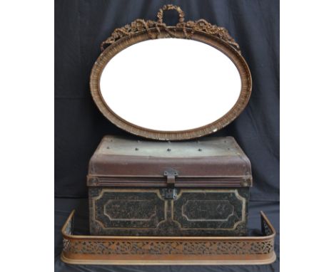 An early Edwardian pierced fender; oval wall mirror, decorated with ormolu swags and fauna; a tin trunk (3).
