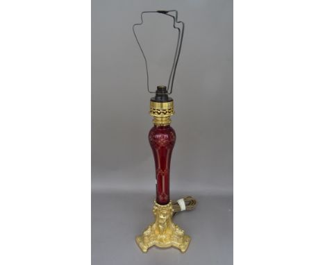 A Victorian style gilt metal and etched ruby glass table lamp, the triform base cast with a putto playing a mandolin, with sh