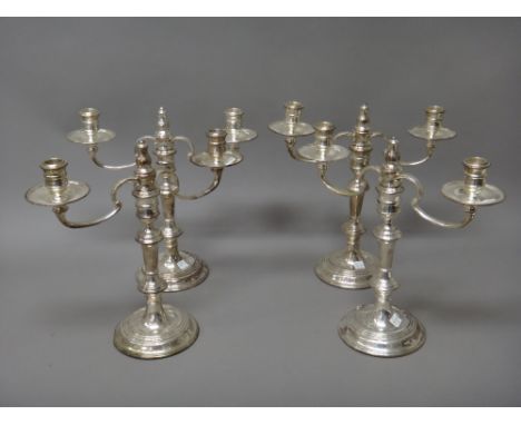 A set of four silver two light table candelabra, each with scrolling arms and raised on a circular base, (loaded), height 32c