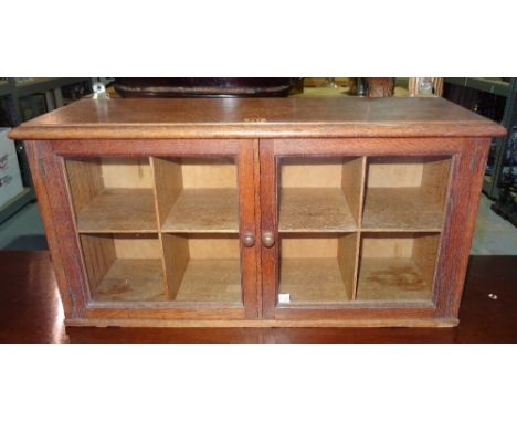 In the manner of Heals; a light oak wall cupboard, the pair of glazed doors enclosing a pigeon hole interior, 69cm wide x 35c
