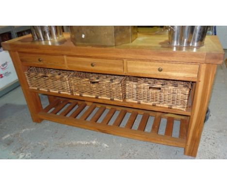 A 20th century oak sideboard, with three drawers and a two tier shelf, with three wicker baskets, on block supports, 180cm wi