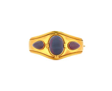A Victorian gold and carbuncle garnet set oval hinged bangle, circa 1860, mounted with the principle oval carbuncle garnet, w