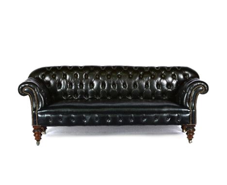 A Victorian and later studded black leather upholstered button back Chesterfield sofa, with rollover arms on carved and turne