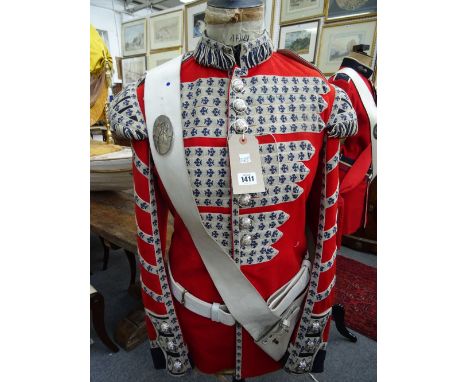 A Scottish military officer's red tunic, sash and belt, displayed on an ebonised wood and shaped tailor's dummy, 160cm.