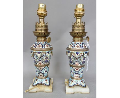 A pair of French champlevé enamel oil lamps, converted, circa 1880, each raised on a shaped hardstone plinth, 22cm high , exc