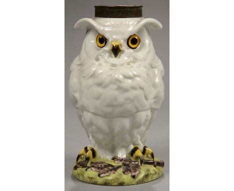 A FRENCH PORCELAIN OWL NOVELTY OIL LAMP BASE WITH VIVID YELLOW AND BLACK EYES, PERCHED ON A GREEN MOUND WITH OAK LEAVES, BRAS
