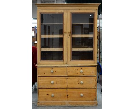 A VICTORIAN WAXED PINE LINEN PRESS, THE UPPER PART FITTED WITH TWO TRAYS AND ONE SHELF ENCLOSED BY GLAZED DOORS, 208CM H; 128