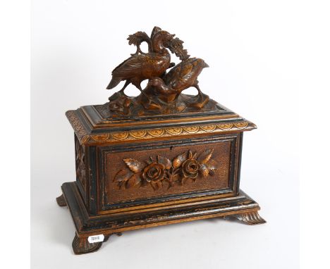 A 19th century carved and stained wood Black Forest tea caddy, with fitted interior, the rising lid surmounted by carved bird