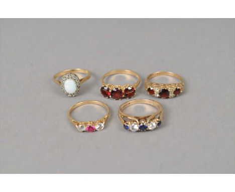 Two 9ct gold garnet rings, together with a 9ct gold opal ring, a 9ct gold three stone paste ring and a further 9ct gold ring,