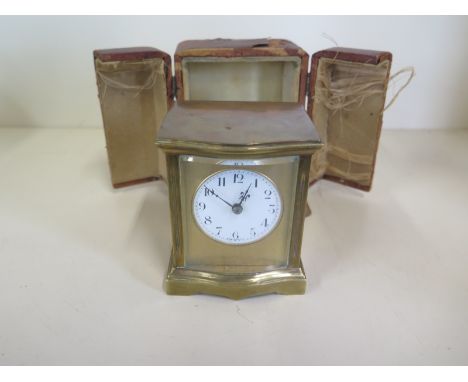 A brass time piece carriage clock with serpentine front, 9.5cm tall with outer case, ticks but stops, case good, outer case w
