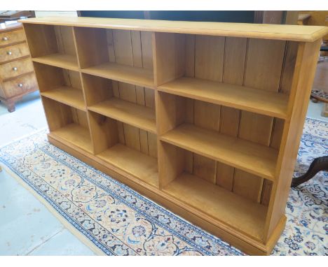 A light oak modern triple fronted open bookcase on a plinth base  107cm H x 203cm x 28cm - in clean polished condition 