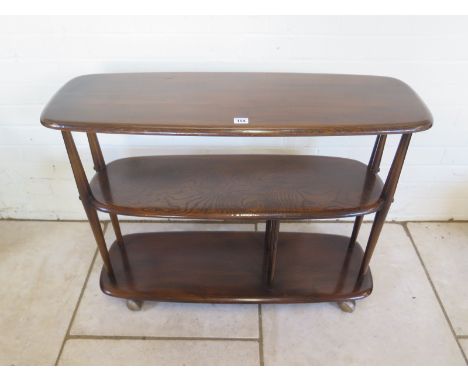 A dark Ercol two tier shelving unit on castors, with Ercol label to its underside, approximately 92cm wide, 71cm high and 31.