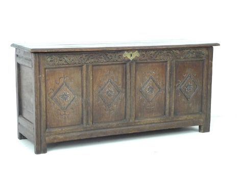 An 18th century oak blanket chest, with two plank lift lid, four panel front carved with rosettes in diamond shaped borders, 