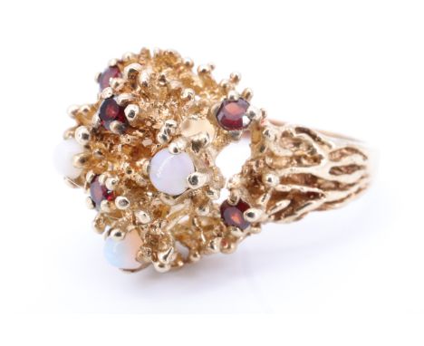 A 1970s naturalistic dress ring, formed with six small garnets and three opal cabochons enriching a corral like setting which