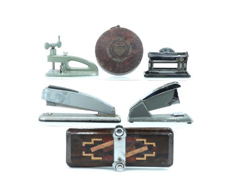 Four vintage staplers and hole punches, together with a Chesterman Bakelite architect's measure and a tie press
