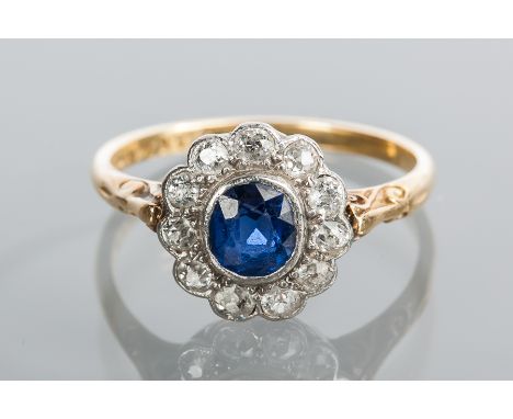 EDWARDIAN SAPPHIRE AND DIAMOND CLUSTER RING
of flower design, set with a central oval blue sapphire surrounded by diamonds, m