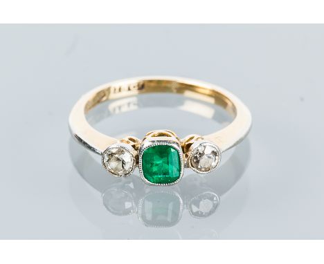 EMERALD AND DIAMOND THREE STONE RING
set with a central step cut emerald flanked by two brilliant cut diamonds, in eighteen c