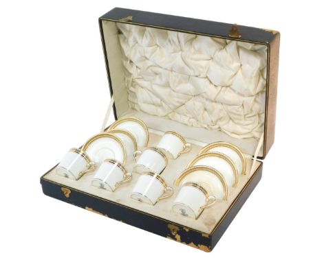 A Crescent porcelain coffee can set, produced for Harrods Ltd, on plain white ground with gilt floral border, comprising six 