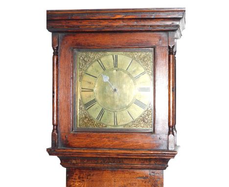An 18thC country oak long case clock, with plain hood, small arched top trunk door and stepped base, the brass dial inscribed