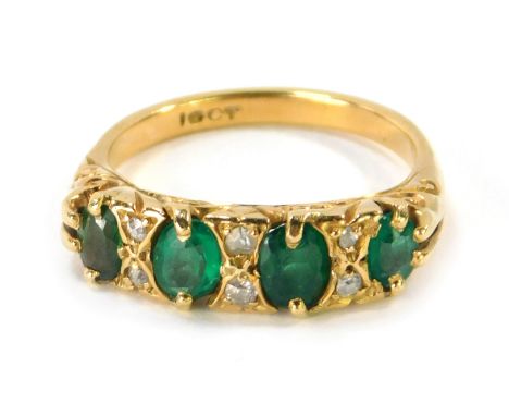 An 18ct gold emerald and diamond gypsy ring, set with four oval cut emeralds, and six tiny diamonds, with scroll design sides