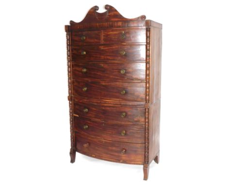 A William IV mahogany bow front tallboy or chest on chest, with scroll pediment, bobbin turned uprights, graduated drawers wi