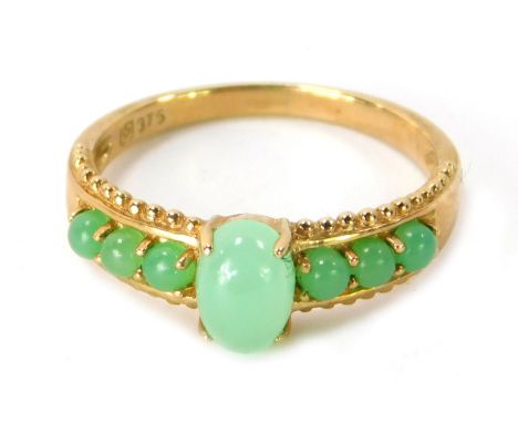 A 9ct gold jade set dress ring, the central raised oval jade in four claw setting with three spherical jade beads to each sho