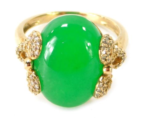 A 9ct gold jade dress ring, the central oval cut light green jade, with bow design shoulders, set with tiny diamonds, ring si