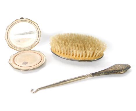 Three items of silver, comprising a silver handled hair brush, a silver octagonal compact, and a silver handled button hook, 