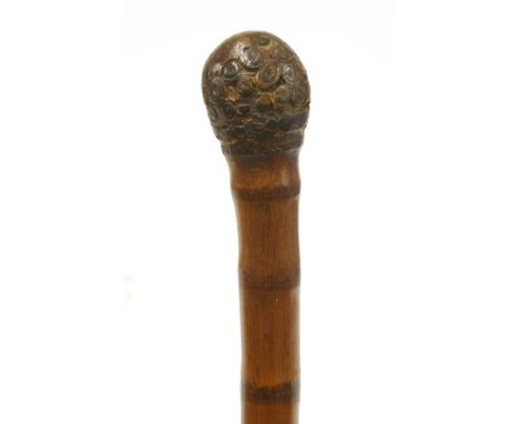 A Chinese bamboo walking stick,with carvings of female faces on the shaft, a screwed brass cap on the end concealing a three-