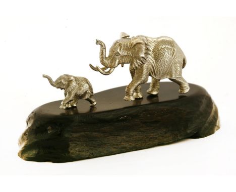 A contemporary silver sculpture of an elephant, mother and baby,by Patrick Mavros, Zimbabwe,on a naturalistically carved ebon