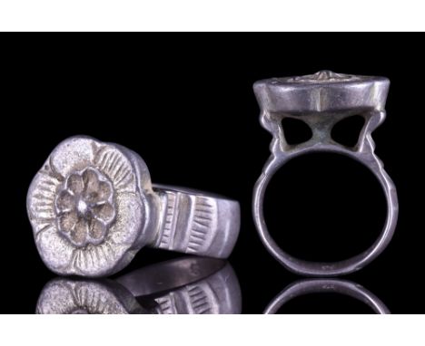 European, ca. 1400 AD. A solid silver finger ring comprising a broad, flat-section hoop with incised shoulders and a large fl