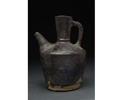 Kashan, Persia, ca. 1200-1300 AD. A ceramic jug featuring a distinctive, rotund body resting upon a circular, unglazed base. 