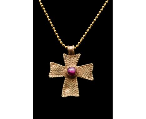 Ca. 600-800 AD. A gold cruciform pendant with a rounded suspension loop, arms of approximately equal length, slightly flaring