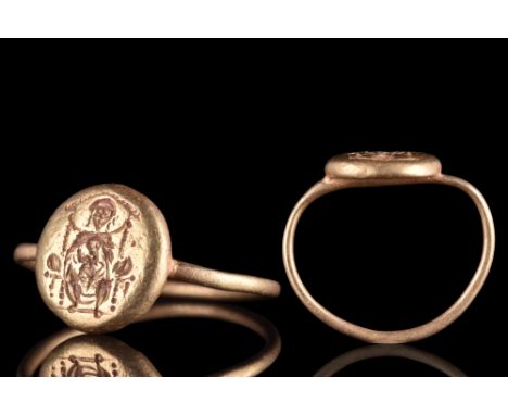 Ca. 600 AD. A gold finger ring comprising a round-section hoop and an applied circular bezel bearing an intricately engraved 